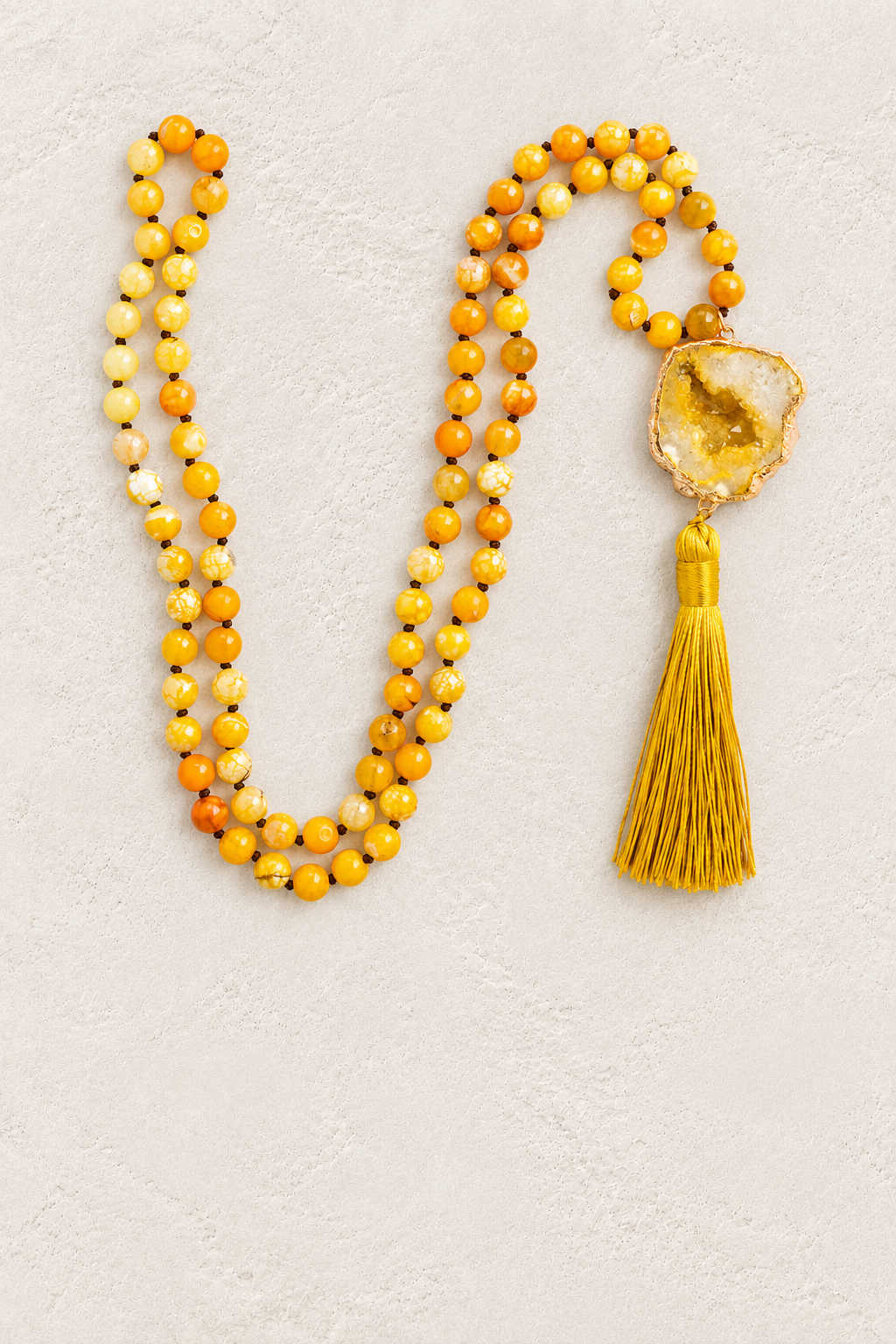 Orange Agate Slice Tassel Necklace on warm ivory plaster background