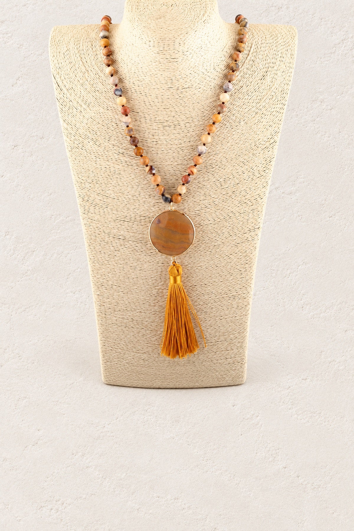 Orange Stone Tassel Necklace on warm cream plaster background