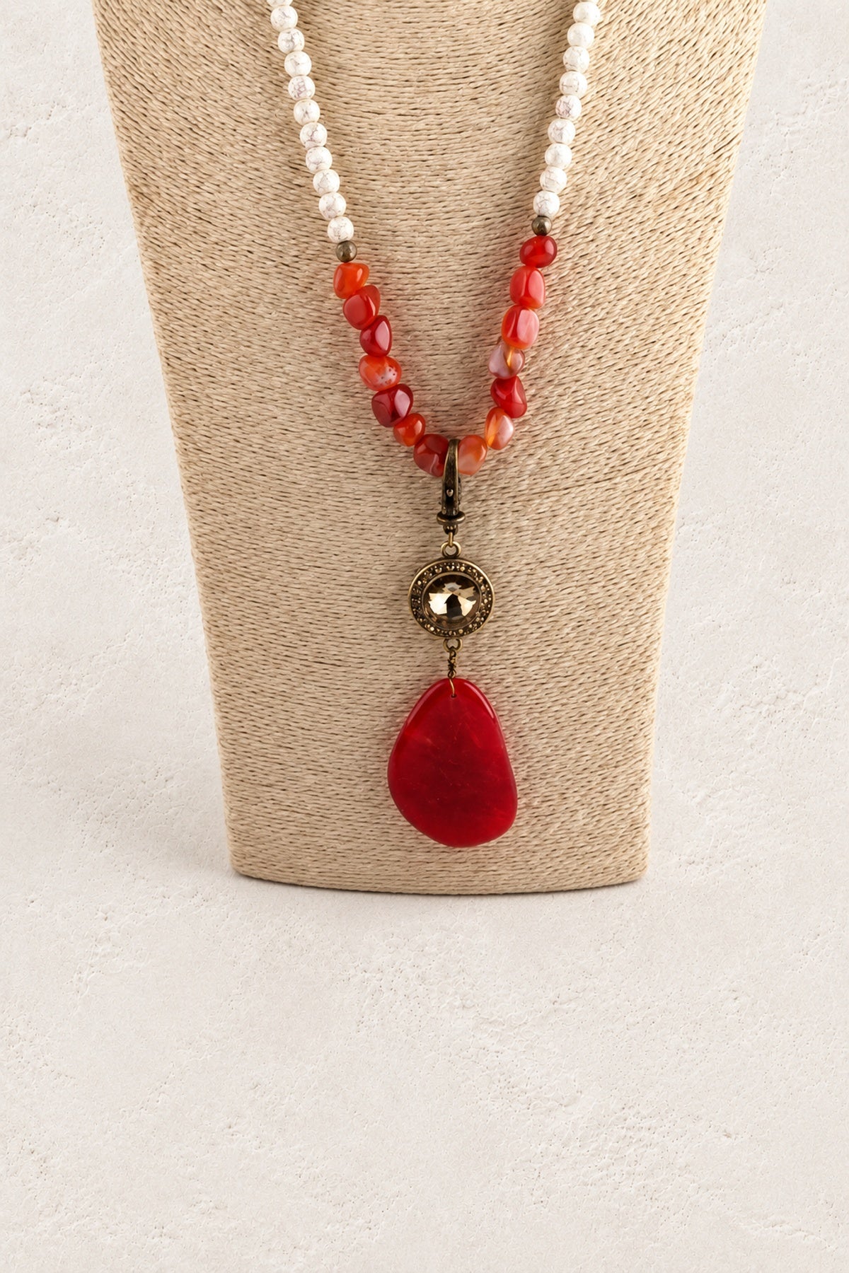 
                  
                    Red Stone Tribal Teardrop Necklace on warm cream plaster background
                  
                