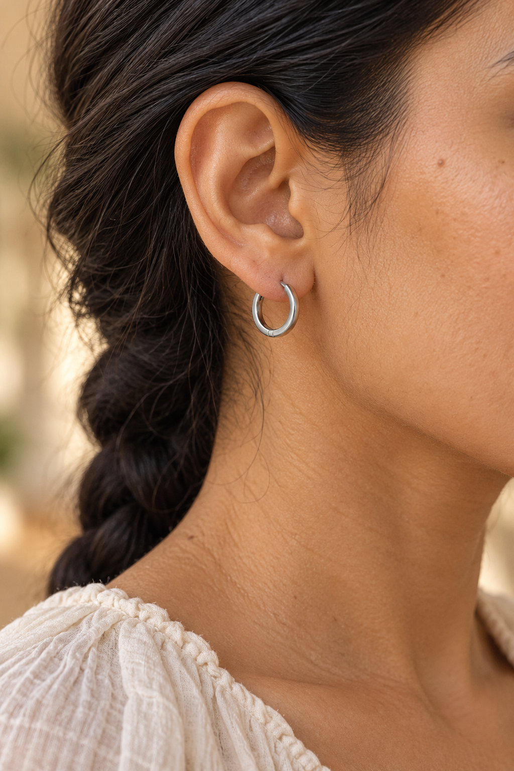 
                  
                    Close-up of Riva Silver Flat Hoop Earrings worn on a boho chic model
                  
                