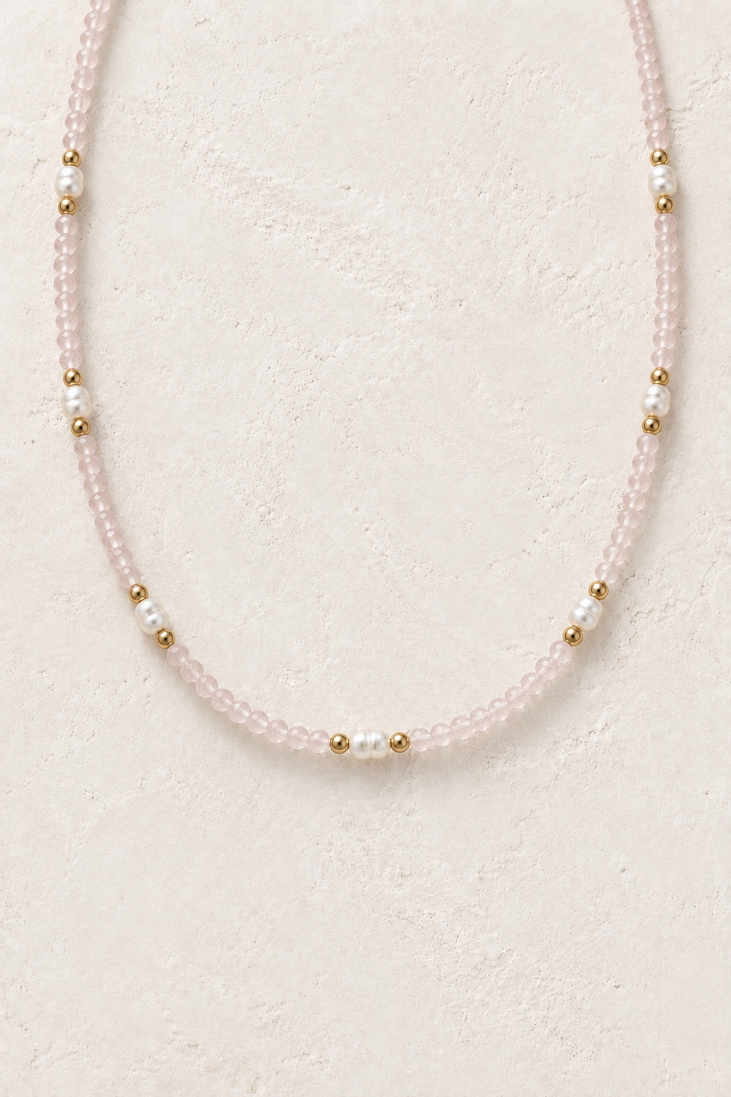 Rosavelle Rose Quartz gold-detail necklace with pearl accents on a neutral background