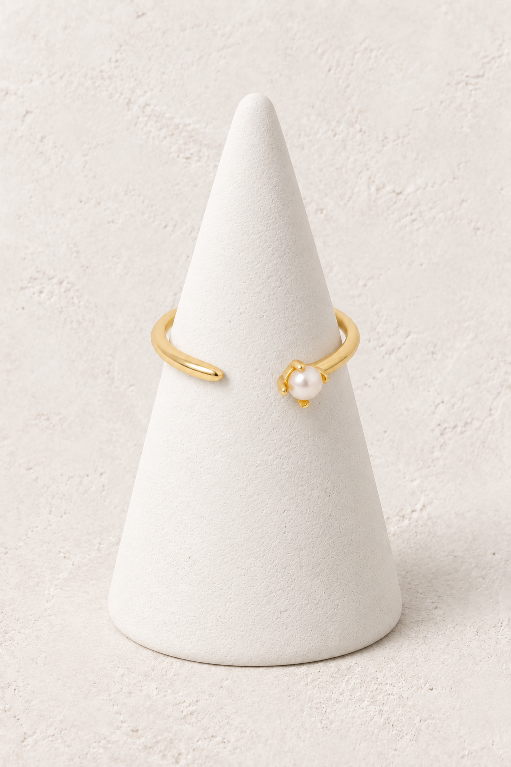 Serene Pearl Tip Ring on a white display cone against a warm textured background