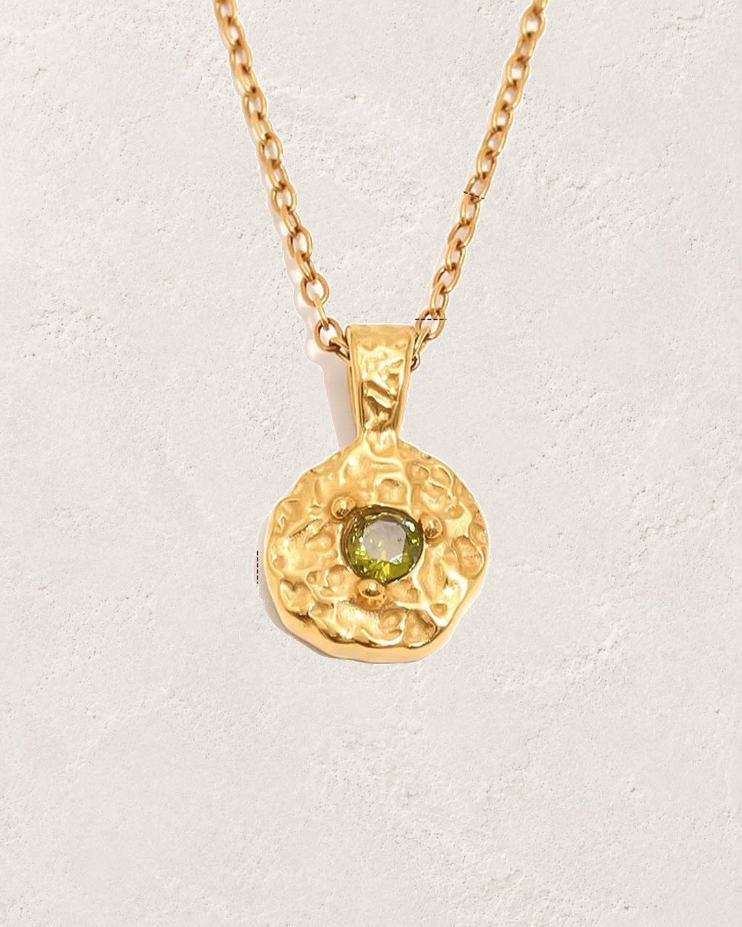 Solara August peridot birthstone necklace on cream plaster background