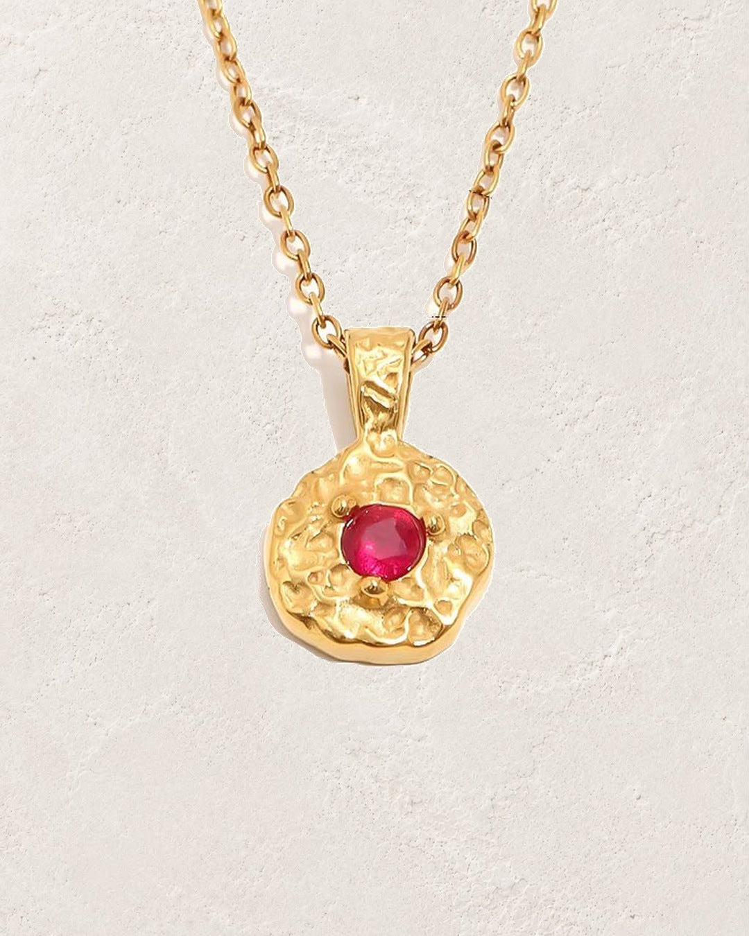 Solara January garnet birthstone necklace on cream plaster background