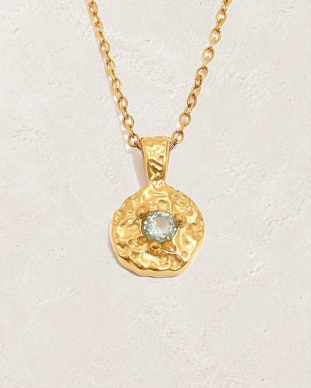 Solara March aquamarine birthstone necklace on cream plaster background