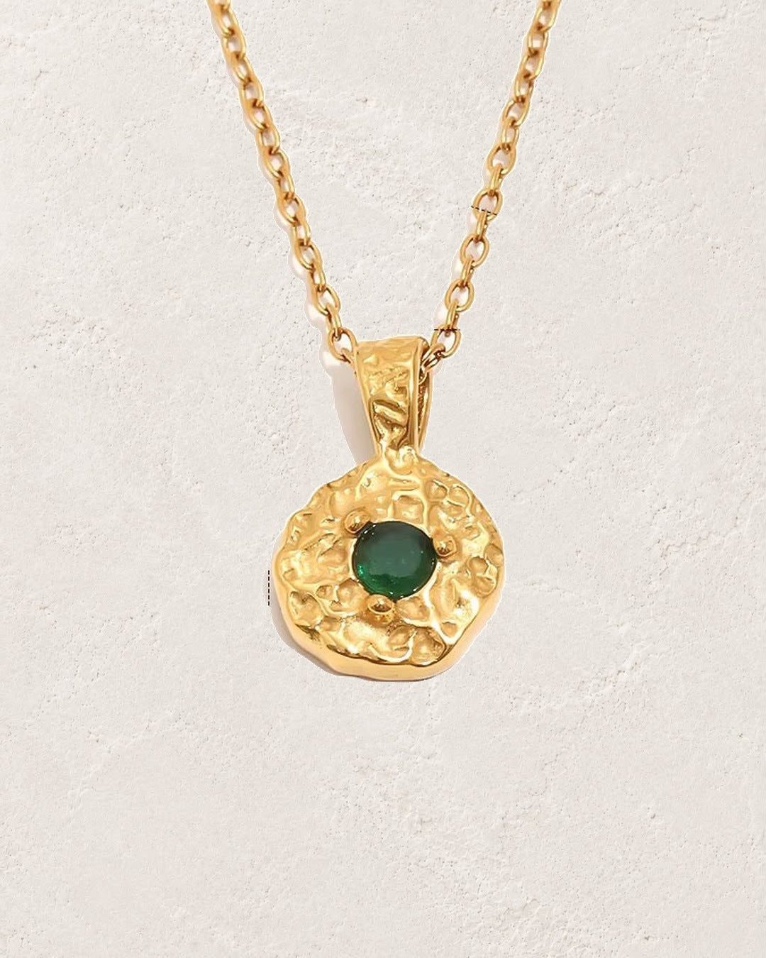Solara May emerald birthstone necklace on cream plaster background