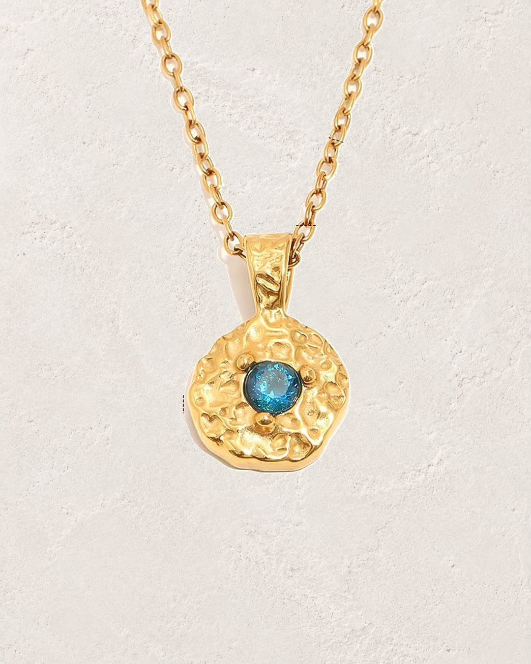 Solara September sapphire birthstone necklace on cream plaster background