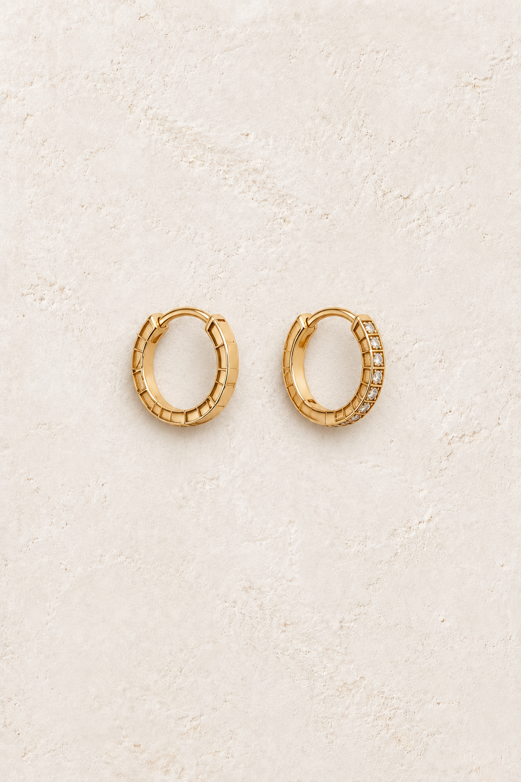 Talia engraved pavé gold huggies on warm ivory textured background