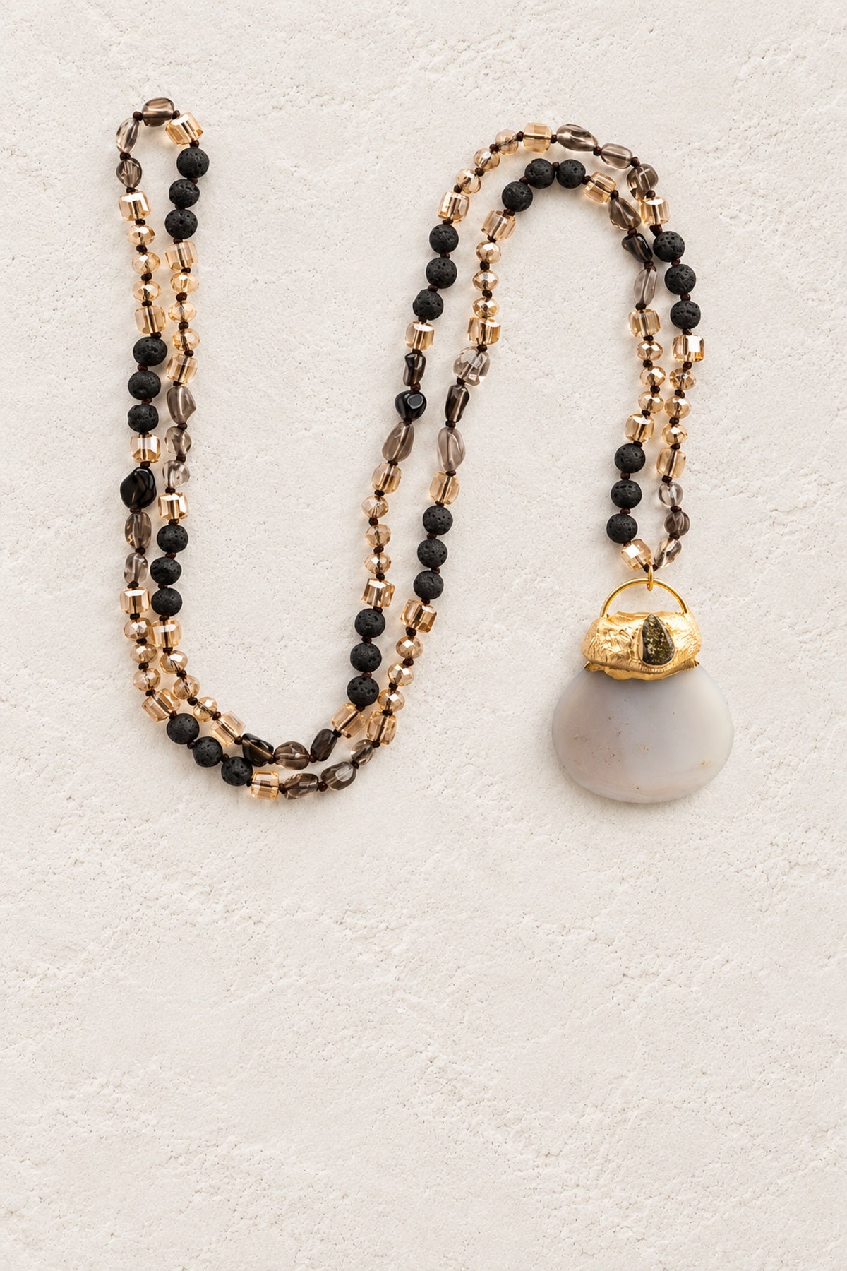 Tribal Mixed Stone Pendant Necklace on warm cream plaster background