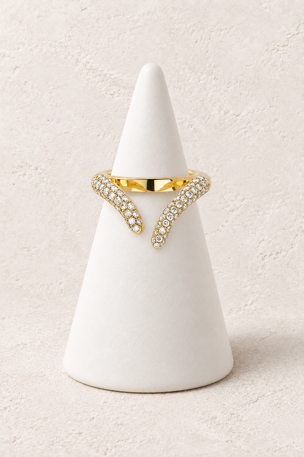Vela Crystal Chevron Ring on a white display cone against a warm textured background