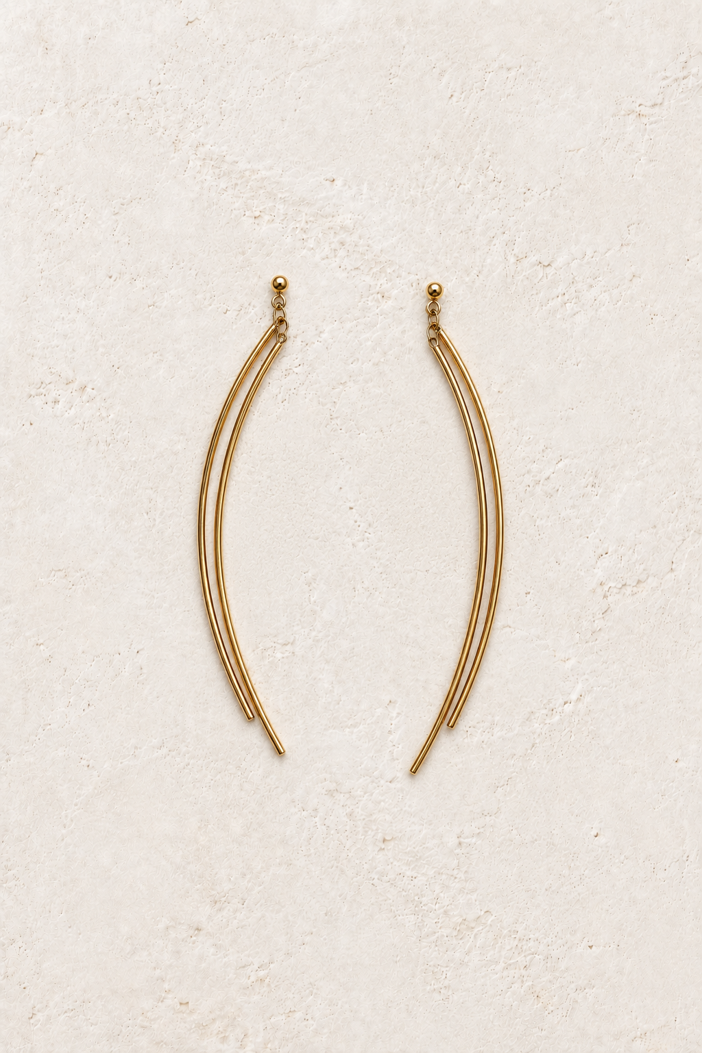 Vela Twin Arc Drop Earrings on warm ivory textured background