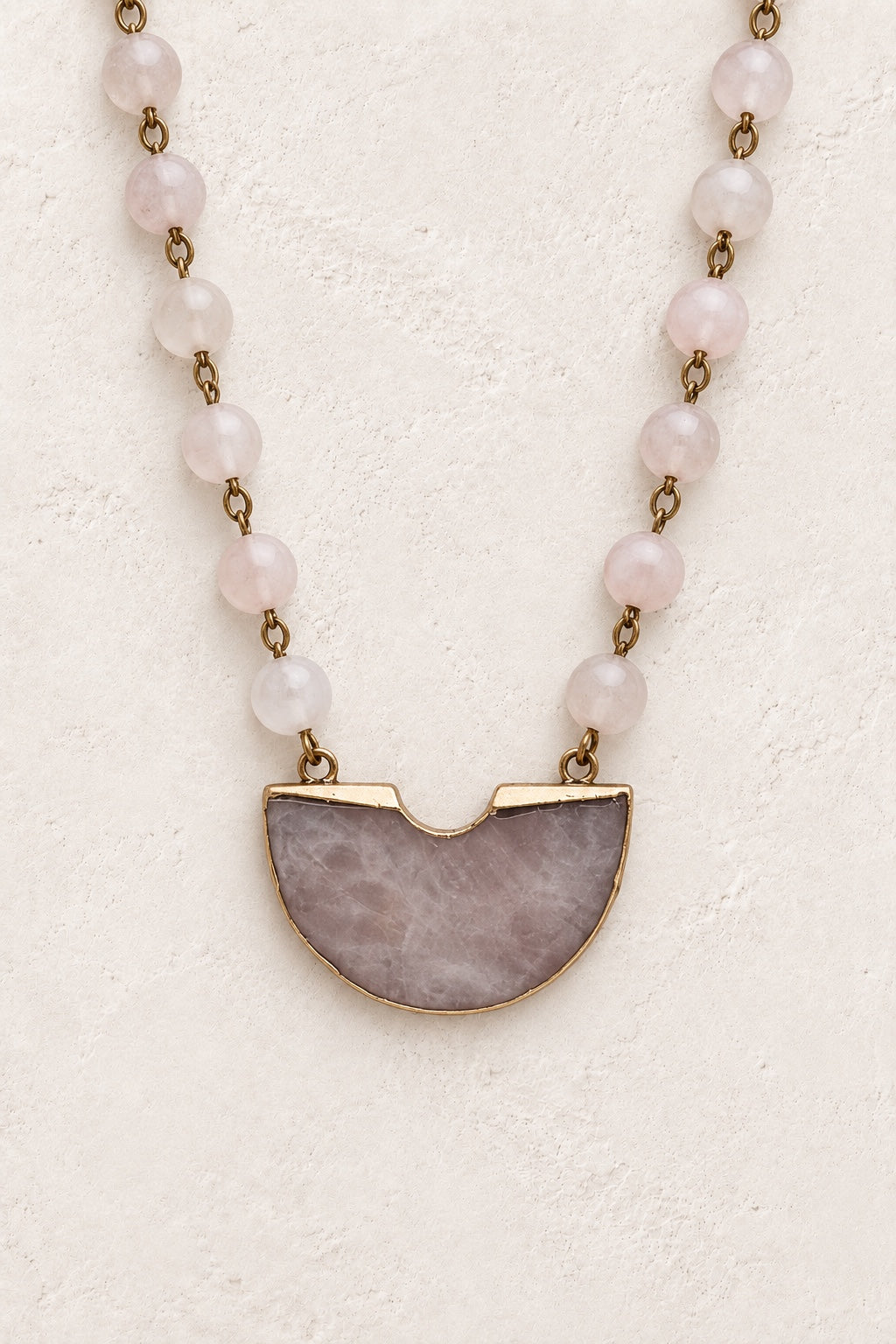 Velmira Rose Quartz beaded half-moon statement necklace on a neutral background