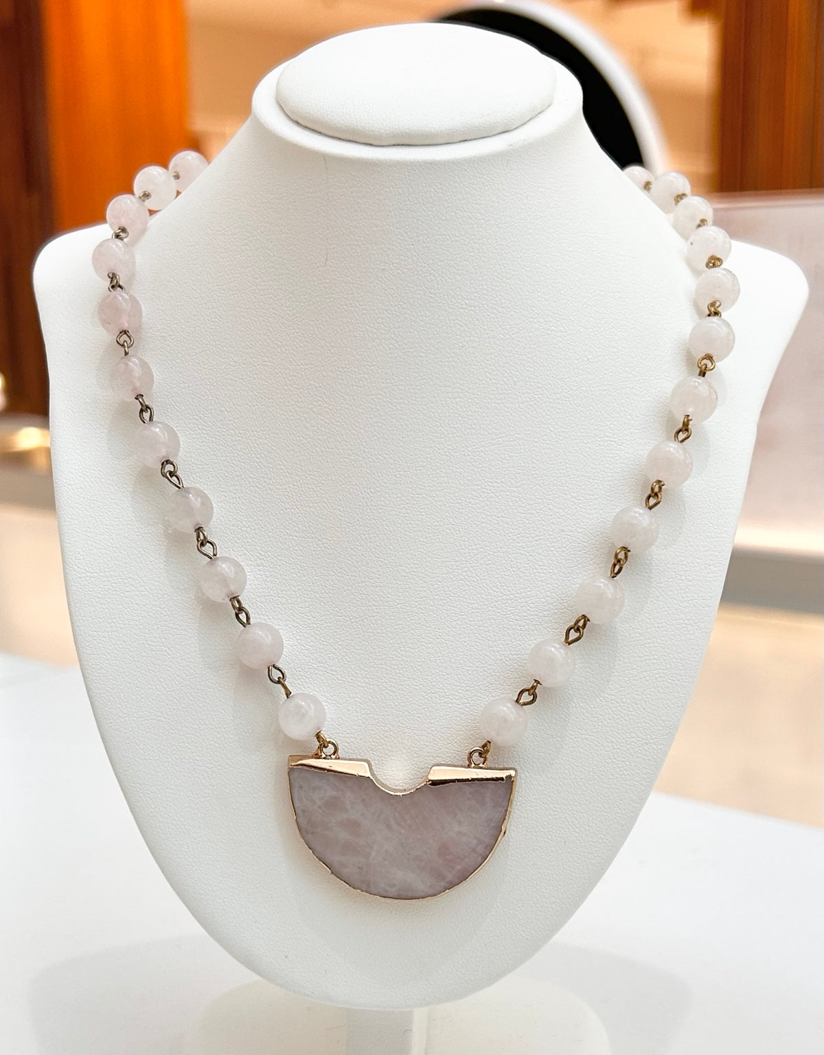 
                  
                    Velmira Rose Quartz gold-plated statement necklace displayed on a jewellery bust
                  
                